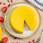 Overhead of the vegan cheddar cheese with a cheese knife to the right and a triangle slice of cheese and tomatoes to the left