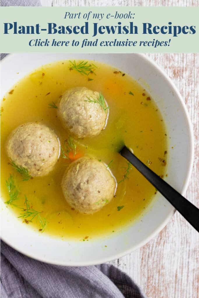 3 matzo balls and broth in a white bowl with a black spoon and a gray napkin