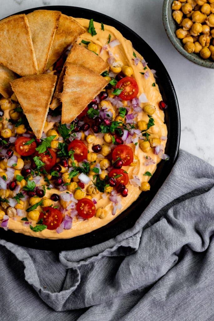 Loaded vegan oil free hummus on a black plate with a gray napkin