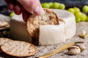 A cracker cutting into soft vegan brie