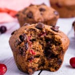 A vegan cranberry muffin with a bite taken out
