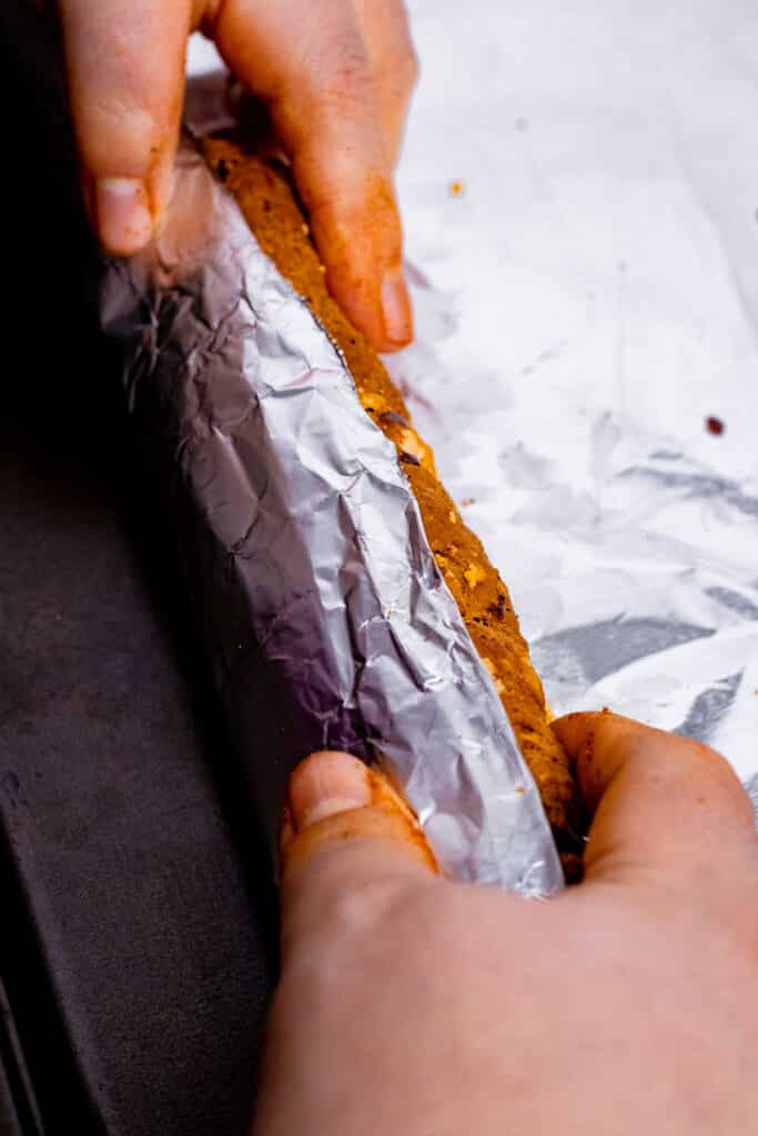 Rolling a raw sausage in heavy duty tin foil