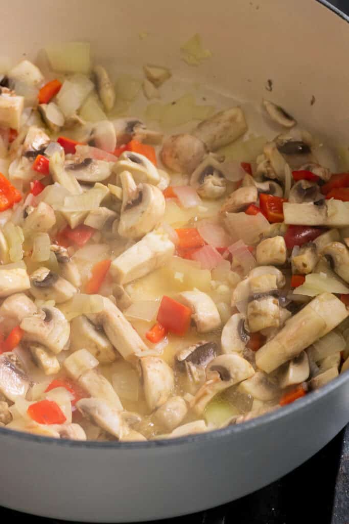 Cooking down the mushrooms, peppers and onions in a pot