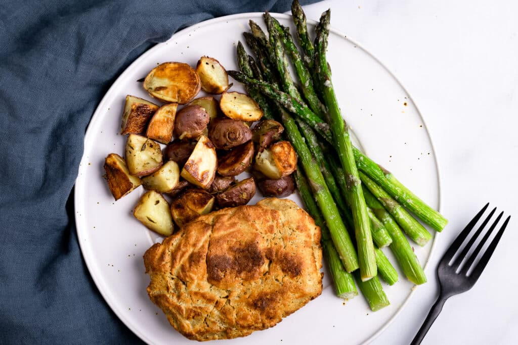 Seitan Chicken on a plate with roasted potatoes and asparagus