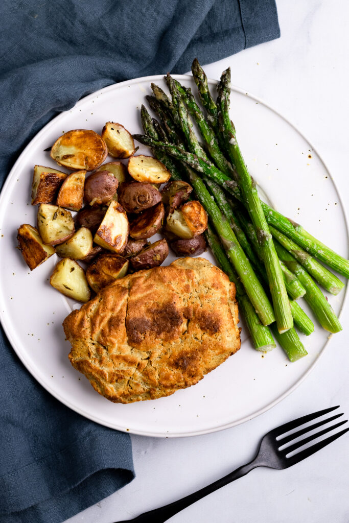 Seitan Chicken on a plate with roasted potatoes and asparagus