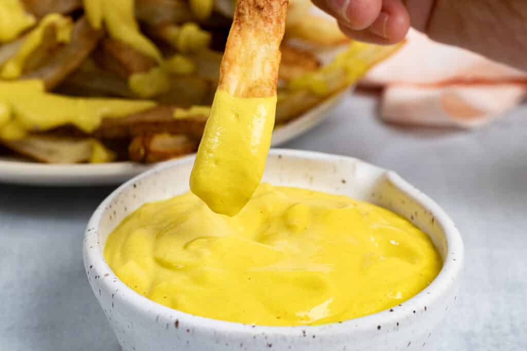 Fry being dipped into sauce
