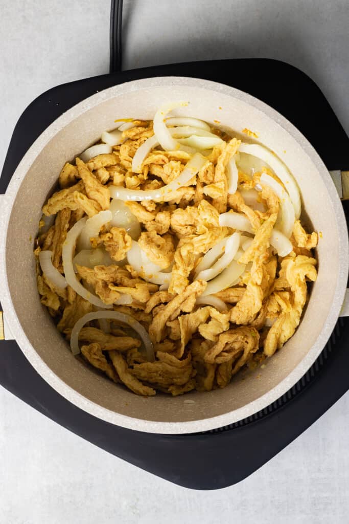 Cooking down the soy curls and onions in the pot