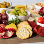 Charcuterie board filled with olives, fruits, vegan cheeses and meats