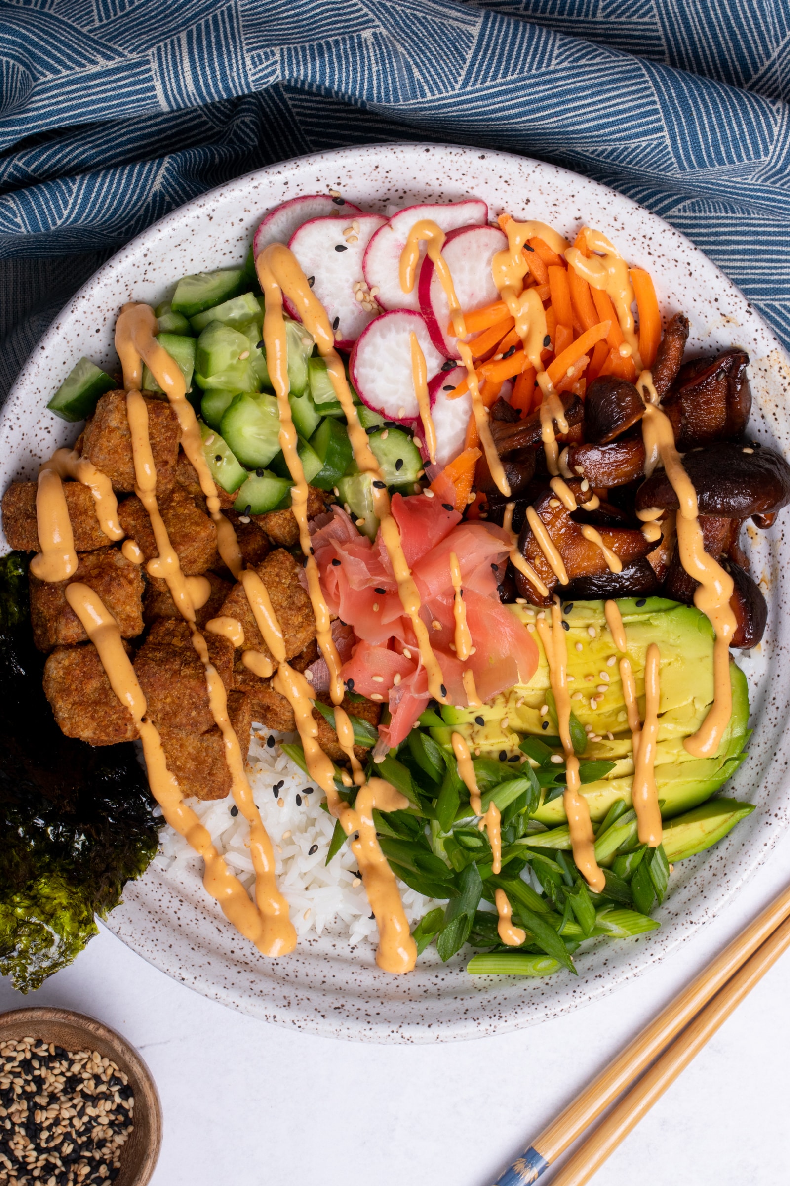 vegan sushi bowl topped with sriarcha sauce.