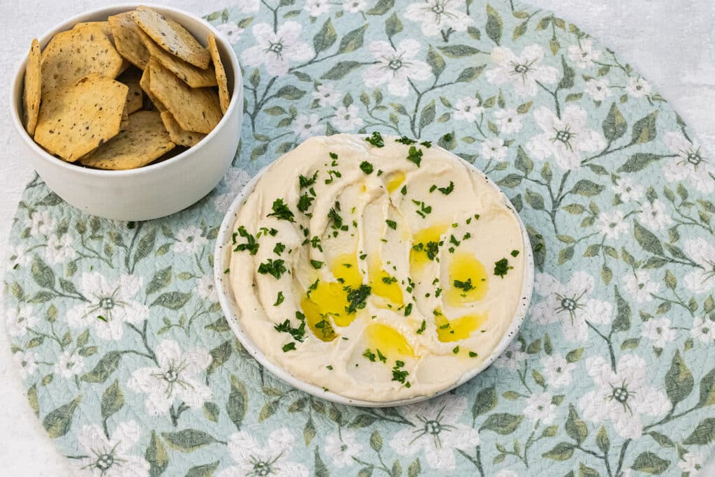 Butter bean hummus on a plate with oil on top and crackers.