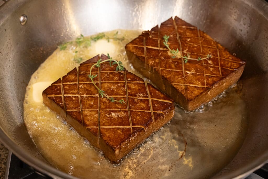 Vegan tofu steaks being made in a pan.