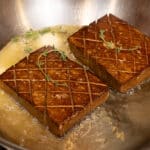 Vegan tofu steaks being made in a pan.