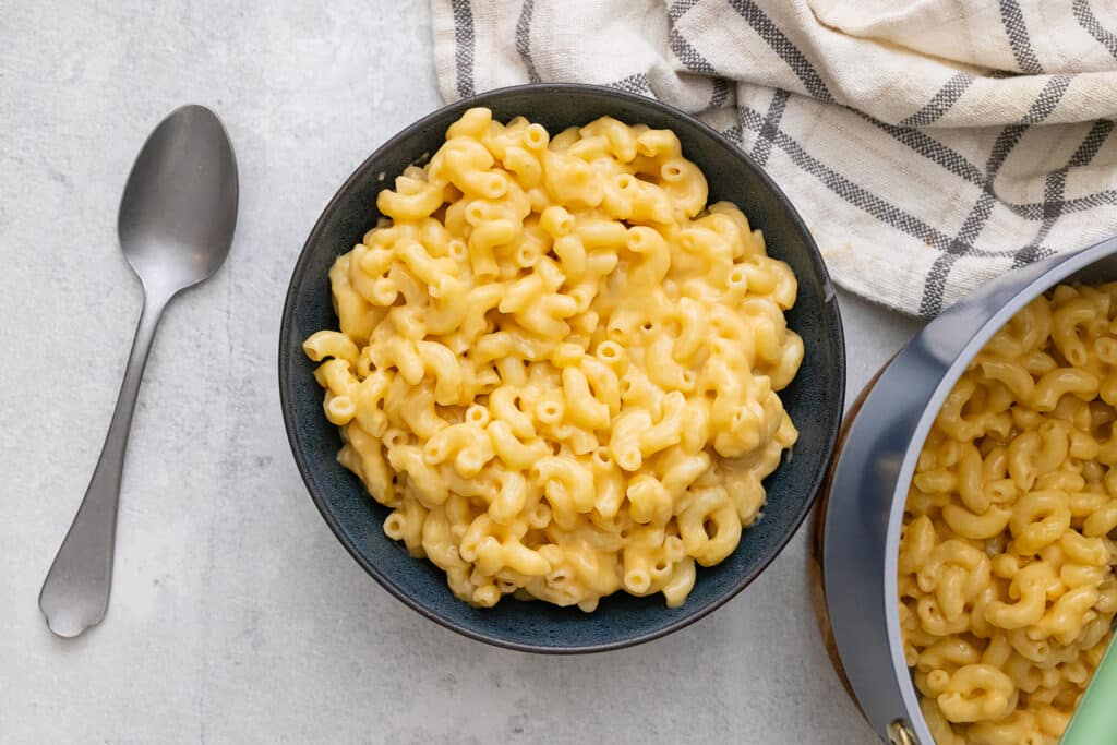 Vegan mac and cheese in a bowl with a spoon nearby.