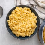 Vegan mac and cheese in a bowl with a spoon nearby.