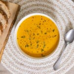 Carrot and Sweet Potato Soup in a bowl with some bread.
