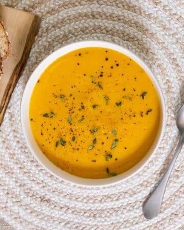 Carrot and Sweet Potato Soup in a bowl with some bread.